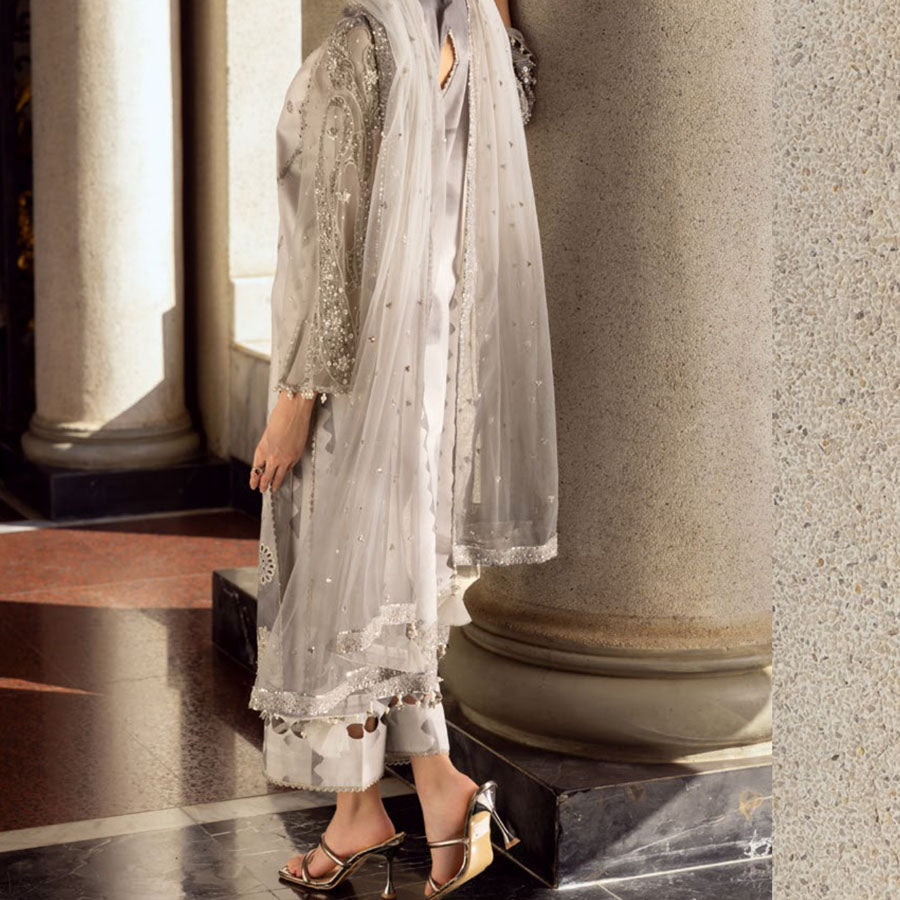 Charizma Festive Unstitched Collection 2025 – Two models wearing elegant embroidered Pakistani suits in pastel blue and golden yellow, featuring intricate handwork, sequins, and delicate embellishments, perfect for Eid celebrations and festive occasions.