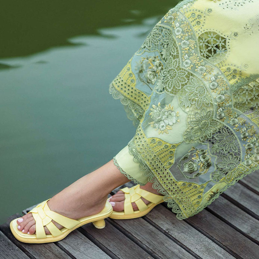 A model wearing a pastel embroidered lawn suit, featuring delicate floral patterns and a matching dupatta, ideal for summer occasions, sitting in a garden setting, showcasing traditional elegance and comfort, wearing a chickenkari embroidered dress.