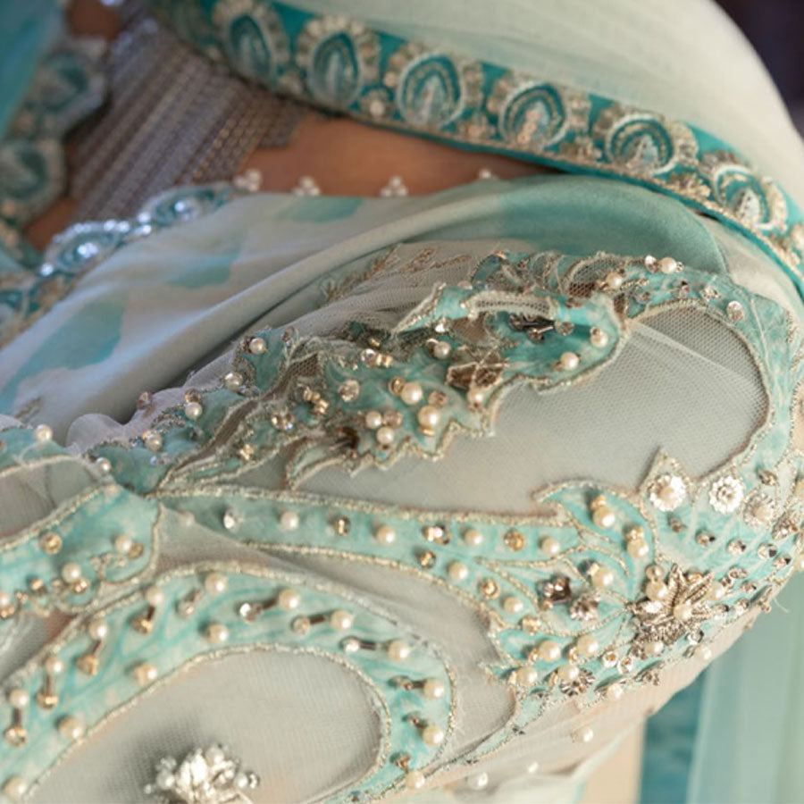 Charizma Festive Unstitched Collection 2025 – Two models wearing elegant embroidered Pakistani suits in pastel blue and golden yellow, featuring intricate handwork, sequins, and delicate embellishments, perfect for Eid celebrations and festive occasions.