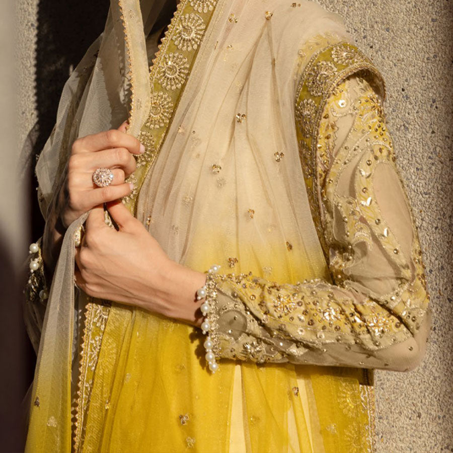Charizma Festive Unstitched Collection 2025 – Two models wearing elegant embroidered Pakistani suits in pastel blue and golden yellow, featuring intricate handwork, sequins, and delicate embellishments, perfect for Eid celebrations and festive occasions.