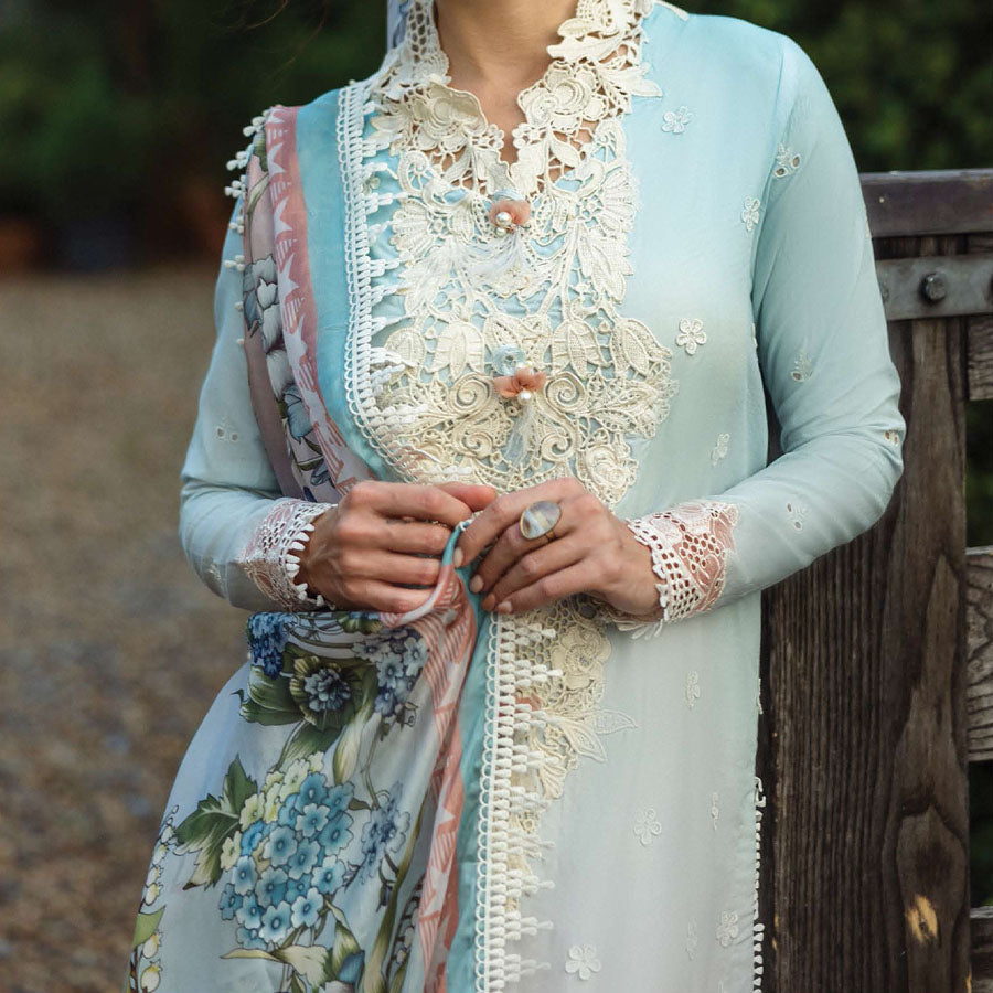 A model wearing a pastel embroidered lawn suit, featuring delicate floral patterns and a matching dupatta, ideal for summer occasions, sitting in a garden setting, showcasing traditional elegance and comfort, wearing a chickenkari embroidered dress.