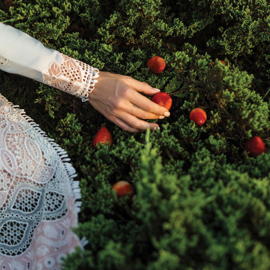 A model wearing a pastel embroidered lawn suit, featuring delicate floral patterns and a matching dupatta, ideal for summer occasions, sitting in a garden setting, showcasing traditional elegance and comfort, wearing a chickenkari embroidered dress.