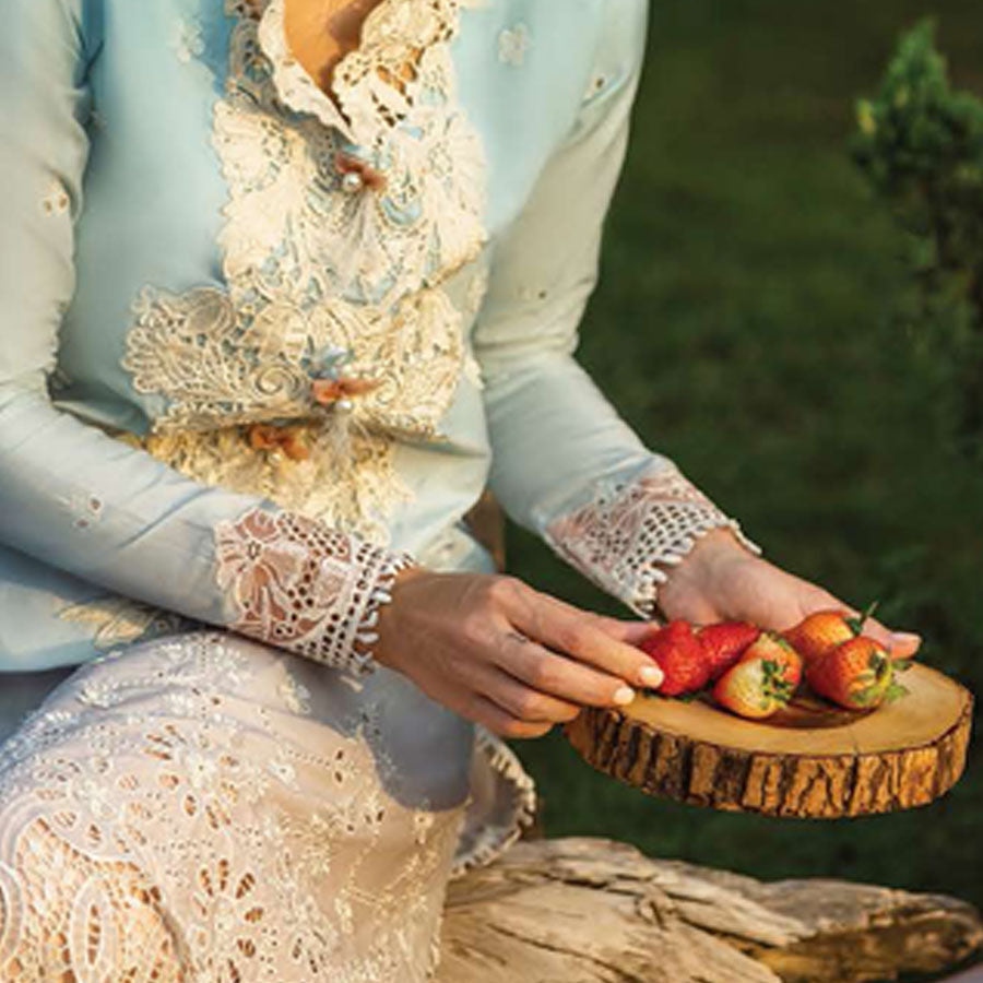 A model wearing a pastel embroidered lawn suit, featuring delicate floral patterns and a matching dupatta, ideal for summer occasions, sitting in a garden setting, showcasing traditional elegance and comfort, wearing a chickenkari embroidered dress.